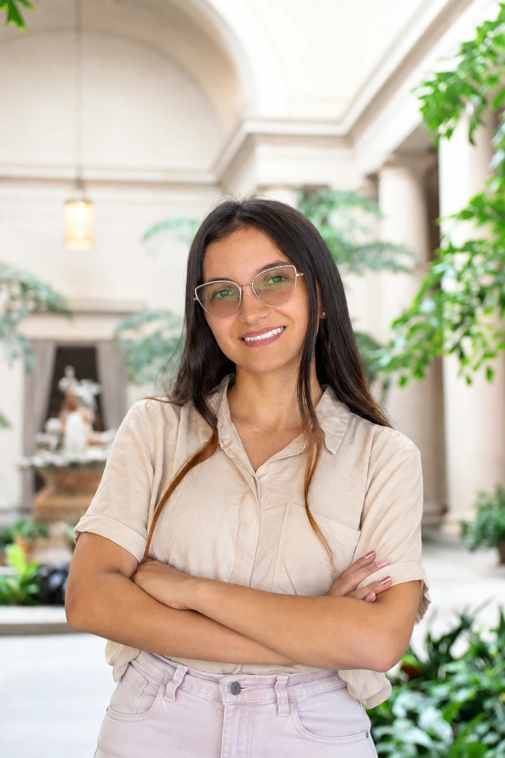 Tati Muñoz sonriendo con los brazos cruzados en un patio con plantas